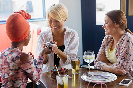 Young woman giving birthday gift to friend in restaurant Stock Photo - Premium Royalty-Free, Code: 6113-09239716