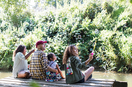 simsearch:6113-08910261,k - Family blowing bubbles on dock in woods Stock Photo - Premium Royalty-Free, Code: 6113-09239971