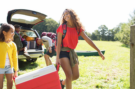 Sisters camping, carrying cooler in sunny field Stock Photo - Premium Royalty-Free, Code: 6113-09239908