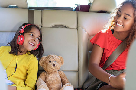Happy sisters and teddy bear riding in back seat of car Stock Photo - Premium Royalty-Free, Code: 6113-09239918