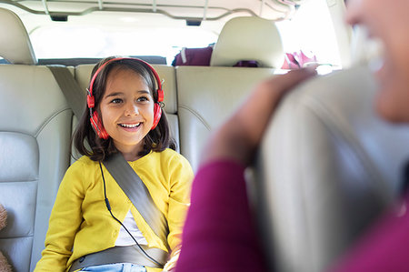 Smiling girl with headphones riding in back seat of car Foto de stock - Sin royalties Premium, Código: 6113-09239920