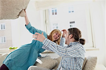 simsearch:6108-06906399,k - A Couple Pillow Fights In Their Living Room Foto de stock - Sin royalties Premium, Código: 6115-06778514