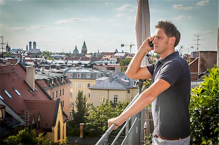 Man On Balcony Using Mobile Phone, Munich, Bavaria, Germany, Europe Stockbilder - Premium RF Lizenzfrei, Bildnummer: 6115-06778669