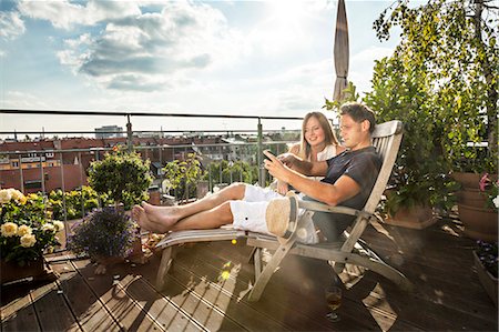 shoeless - Couple On Balcony Using Mobile Phone, Munich, Bavaria, Germany, Europe Stock Photo - Premium Royalty-Free, Code: 6115-06778673