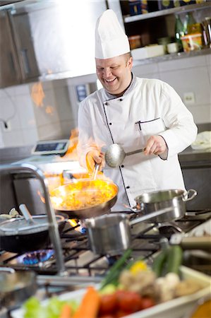 flaming cook - Chef flambeing food in pan Foto de stock - Sin royalties Premium, Código: 6115-06778981