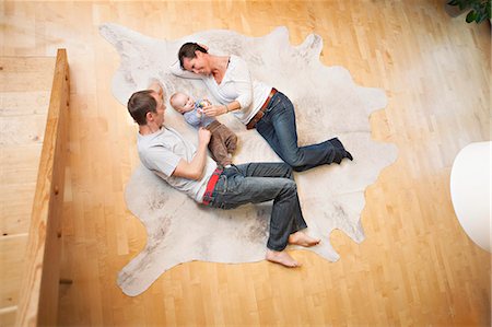 Young family with baby boy relaxes on carpet, Munich, Bavaria, Germany Stock Photo - Premium Royalty-Free, Code: 6115-06779108