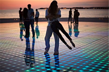 friends hugging - Croatia, Dalmatia, Solar panels as a dance floor, sunset in background Photographie de stock - Premium Libres de Droits, Code: 6115-06732879