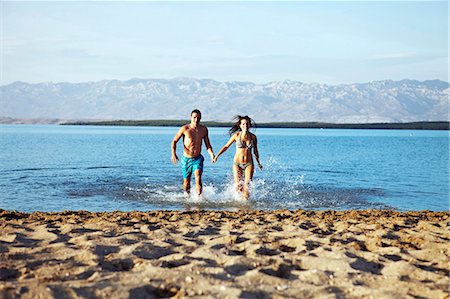 Young couple running on beach Stock Photo - Premium Royalty-Free, Code: 6115-06732806