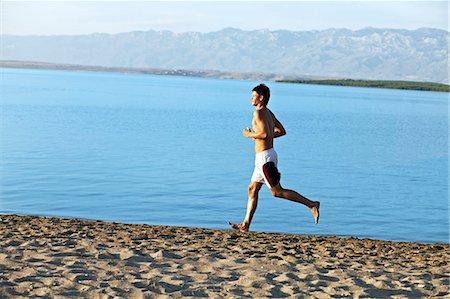 running water - Young man jogging on the beach Foto de stock - Sin royalties Premium, Código: 6115-06732809