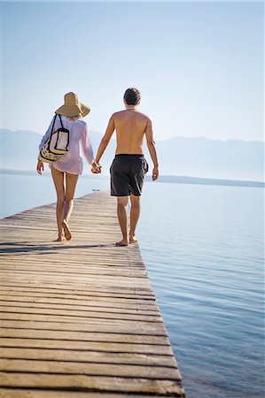 simsearch:6115-06732976,k - Croatia, Young couple in swimwear walking across boardwalk, rear view Fotografie stock - Premium Royalty-Free, Codice: 6115-06732965