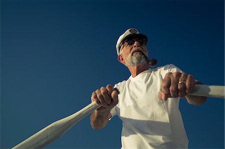 portrait man lifestyle summer closeup - Croatia, Senior man with captain's hat steering sailboat Stock Photo - Premium Royalty-Free, Code: 6115-06733320