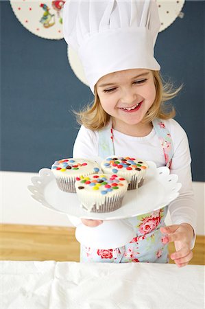 Little girl with chef's hat presenting muffins, Munich, Bavaria, Germany Foto de stock - Sin royalties Premium, Código: 6115-06966931