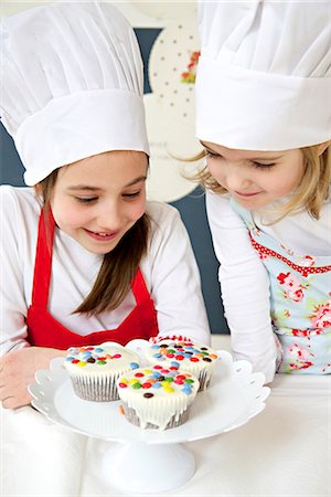 simsearch:6115-07282709,k - Little girl with chef's hat looking at muffins, Munich, Bavaria, Germany Photographie de stock - Premium Libres de Droits, Code: 6115-06966934