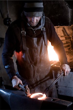 ferradura - Blacksmith shaping horseshoe on anvil, Landshut, Bavaria, Germany Foto de stock - Royalty Free Premium, Número: 6115-06967120