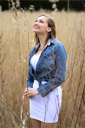 simsearch:6115-07109919,k - Woman in denim jacket stands in a corn field, looking up, Denmark, Europe Photographie de stock - Premium Libres de Droits, Code: 6115-07109819