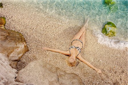simsearch:6115-08105067,k - Sexy young woman in bikini sunbathing on beach, arms outstretched, Dubrovnik, Croatia Foto de stock - Sin royalties Premium, Código: 6115-07282847