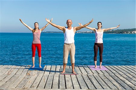 simsearch:6115-06778907,k - People practising yoga on a boardwalk, arms outstretched Stock Photo - Premium Royalty-Free, Code: 6115-07539713