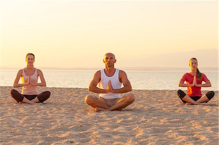 simsearch:6113-07906163,k - People practising yoga on beach, lotus pose Stock Photo - Premium Royalty-Free, Code: 6115-07539716
