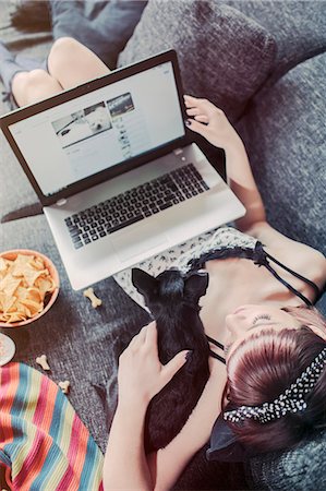 Young woman using laptop alongside her pet dog Photographie de stock - Premium Libres de Droits, Code: 6115-08066499