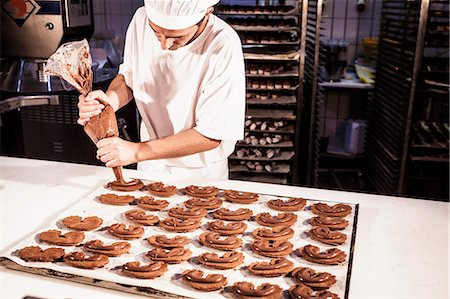 Confectioner uses icing bag decorating cookies Foto de stock - Sin royalties Premium, Código: 6115-08100492