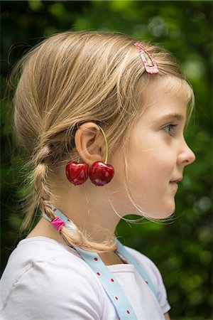 Little girl, cherries dangling from her ears Photographie de stock - Premium Libres de Droits, Code: 6115-08100435