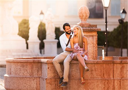 simsearch:6115-07539619,k - Young couple dating and flirting by fountain in town Fotografie stock - Premium Royalty-Free, Codice: 6115-08100629