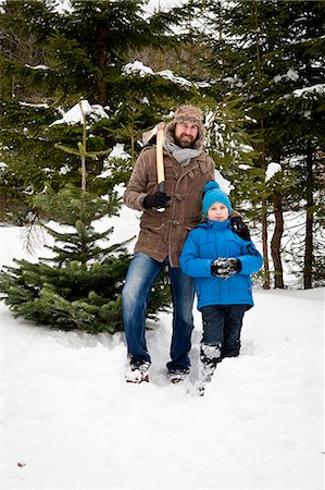 Father and son standing with axe by Christmas tree in snow-covered landscape, Bavaria, Germany Photographie de stock - Premium Libres de Droits, Code: 6115-08100637