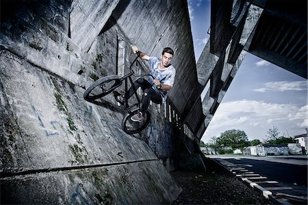 BMX biker performing a stunt on a bridge Photographie de stock - Premium Libres de Droits, Code: 6115-08100905