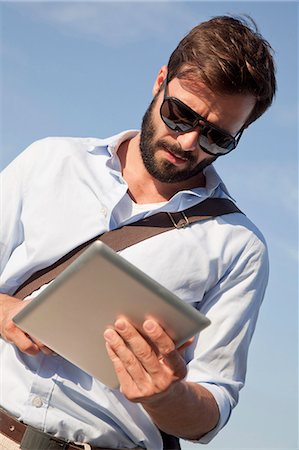 simsearch:6115-08101193,k - Young man using digital tablet outdoors Stock Photo - Premium Royalty-Free, Code: 6115-08100929