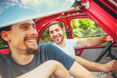 simsearch:6115-08101096,k - Portrait of two young men in red car smiling merrily Stock Photo - Premium Royalty-Free, Code: 6115-08101088