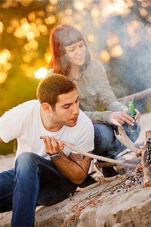 simsearch:6115-08101150,k - Young man arranging firewood at campfire, girlfriend in background, Osijek, Croatia Stock Photo - Premium Royalty-Free, Code: 6115-08101001