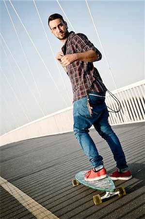 simsearch:6115-08101013,k - Young man skateboarding across bridge Fotografie stock - Premium Royalty-Free, Codice: 6115-08101009
