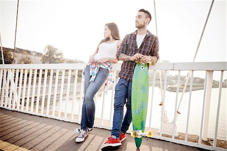 simsearch:6115-08101013,k - Young couple with skateboard waiting on bridge Fotografie stock - Premium Royalty-Free, Codice: 6115-08101014