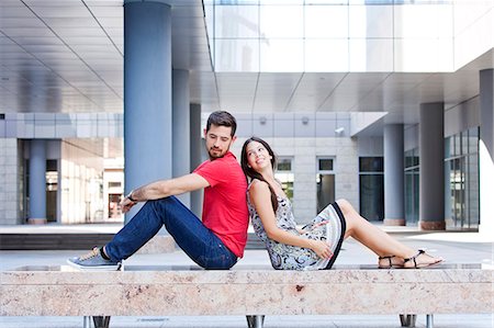 person sitting on bench - Happy young couple sits back to back on campus Stock Photo - Premium Royalty-Free, Code: 6115-08101125