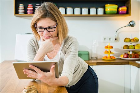 reading glasses - Senior woman in kitchen using tablet pc Stock Photo - Premium Royalty-Free, Code: 6115-08104880