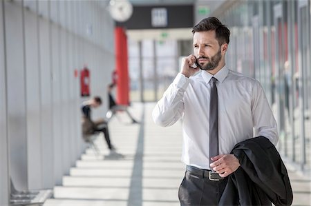 simsearch:6111-06728871,k - Businessman using phone in modern lobby Stock Photo - Premium Royalty-Free, Code: 6115-08104953