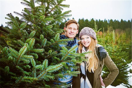 simsearch:6115-08239219,k - Young couple standing by fresh cut Christmas tree Foto de stock - Royalty Free Premium, Número: 6115-08104929