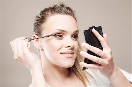 simsearch:6115-08105110,k - Young woman applying mascara Stock Photo - Premium Royalty-Free, Code: 6115-08105084