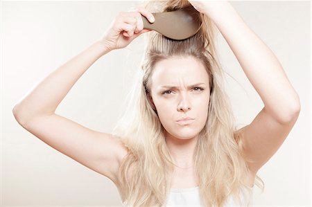 simsearch:6115-08105110,k - Young woman brushing her hair Stock Photo - Premium Royalty-Free, Code: 6115-08105107