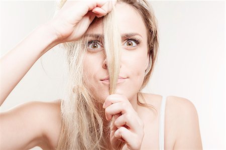 simsearch:6115-08105095,k - Young woman holding strand of hair Stock Photo - Premium Royalty-Free, Code: 6115-08105110