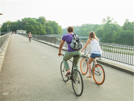 simsearch:6122-08229539,k - Young couple riding bicycle on city bridge Photographie de stock - Premium Libres de Droits, Code: 6115-08239199