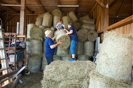 Grandfather and grandchildren stacking bales of hay Photographie de stock - Premium Libres de Droits, Code: 6115-08239134