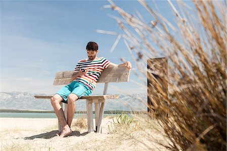 surfboard mobile - Young man using handy on beach Stock Photo - Premium Royalty-Free, Code: 6115-08239244