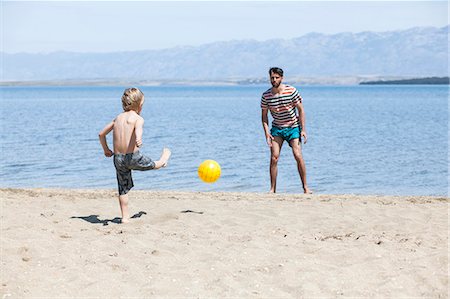 simsearch:6115-08239440,k - Father and son on beach playing with soccer ball Foto de stock - Royalty Free Premium, Número: 6115-08239268