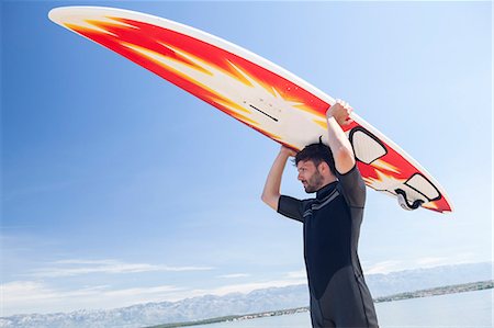 Surfer holding surfboard over head Stock Photo - Premium Royalty-Free, Code: 6115-08239237