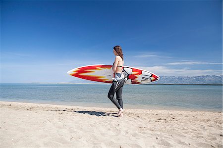 simsearch:6115-08239316,k - Woman carrying surfboard on beach Foto de stock - Sin royalties Premium, Código: 6115-08239235
