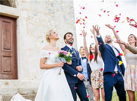 simsearch:6115-08239477,k - Guests throwing rose petals on bride and groom Stock Photo - Premium Royalty-Free, Code: 6115-08239365