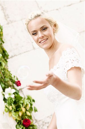 simsearch:6115-08239477,k - Happy bride playing with soap bubbles Stock Photo - Premium Royalty-Free, Code: 6115-08239396