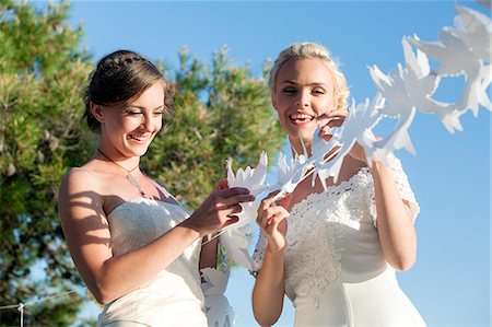 simsearch:6115-07109837,k - Bride and bridesmaid playing with white paper cut out outdoors Stock Photo - Premium Royalty-Free, Code: 6115-08239478