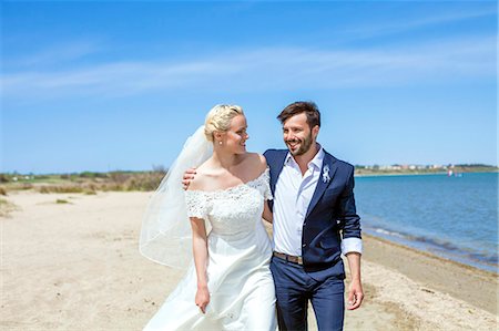 simsearch:6115-08239504,k - Bride and bridegroom walking happily on beach Stock Photo - Premium Royalty-Free, Code: 6115-08239425